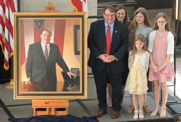 Former Senate President Larry Obhof stands with his family beside his new official portrait.