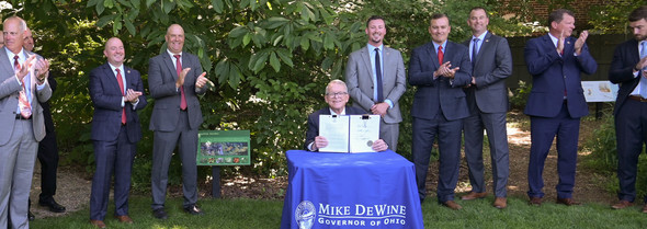 Governor DeWine holds up the newly signed House Bill 377 in the Appalachian Garden of the Ohio Governor's Residence and Heritage Garden .