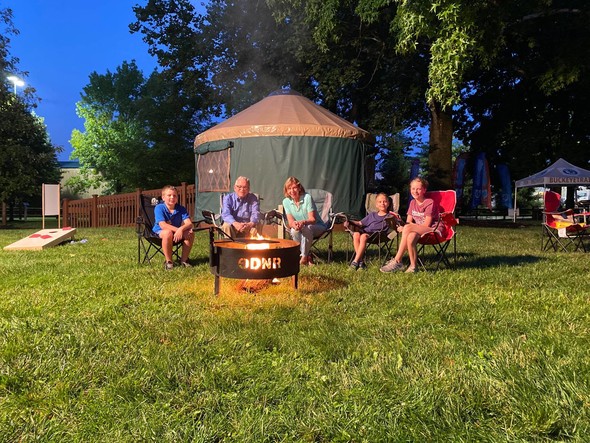 Governor DeWine, First Lady DeWine, and several of their grandkids sit outside of their campsite in the ODNR Natural Resources Park.