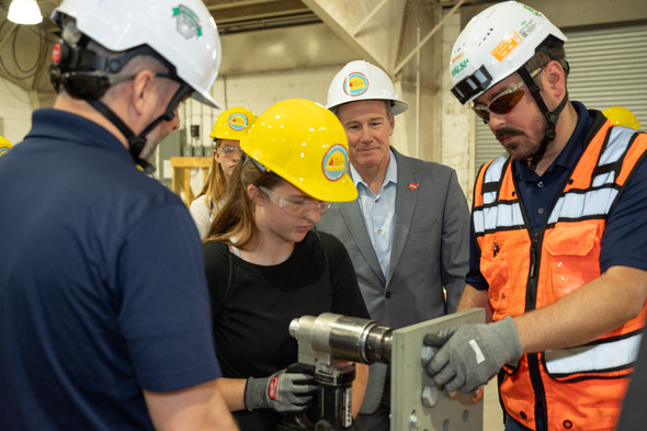 Husted watching female construction student use drill