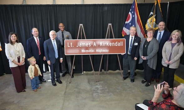 Governor DeWine helping to reveal a highway dedication sign.