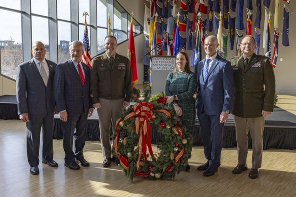 Ohio Lt. Governor Jim Tressel and other event participants pose for a photo alongside wreath featured in Monday’s wreath-laying ceremony.