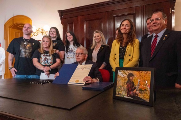Governor holds up signed proclamation recognizing September as Childhood Cancer Awareness Month