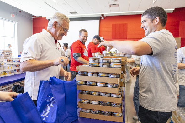 Lt. Governor Tressel next to a next to packed meal bags. 