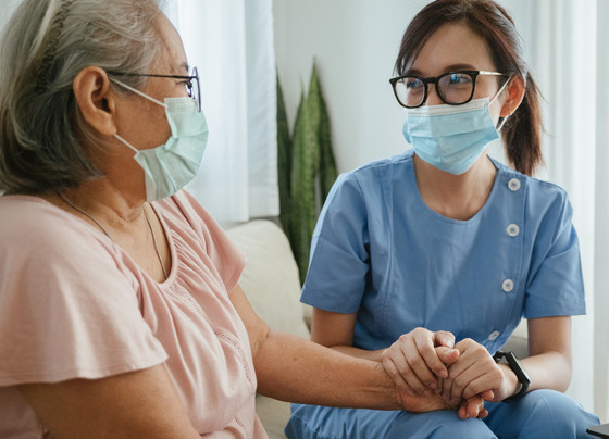 home health nurse holding a patient's hand