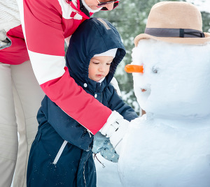 photo of a child and grandparent building a snowman