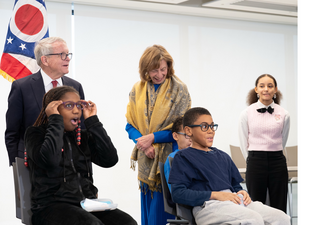 Governor Mike DeWine and First Lady of Ohio Fran DeWine watch children try on glasses
