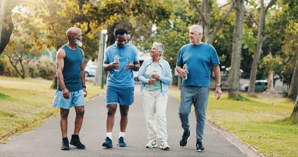 group of four adults in exercise clothes and tennis shoes walking through a metropark