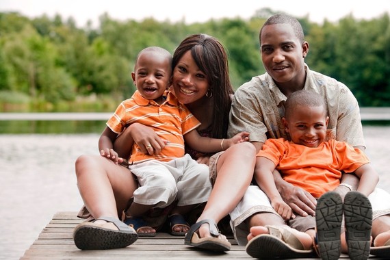  Two African american parents with two little boys sitting on a dock