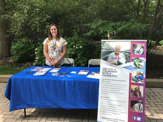 Photo of Megan Naves behind table with literature on ODD at Toledo Zoo for ADA Day