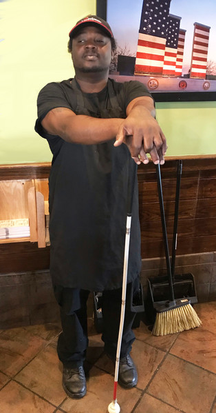 Khaliff Williams stands near a wall with his cane at his job