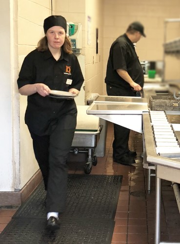  Young woman in university kitchen holding a plate