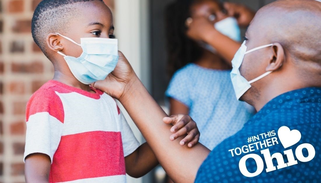Photo of african american man with a mask adjusting mask on a little boy