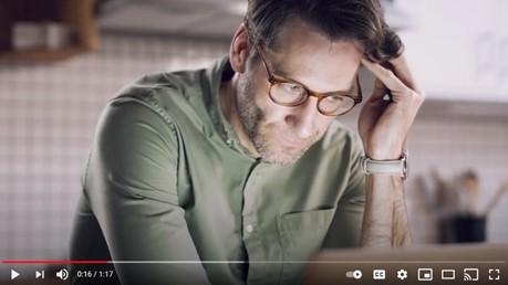 Man in green shirt with glasses holding  his hand to his forehead