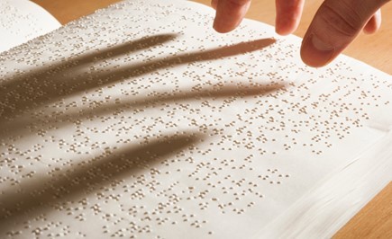 fingers ready to touch a braille piece of paper