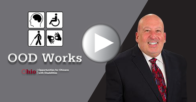 Photo graphic of  play button superimposed over photo of man in suit  with OODWorks logo with disability symbols on the left
