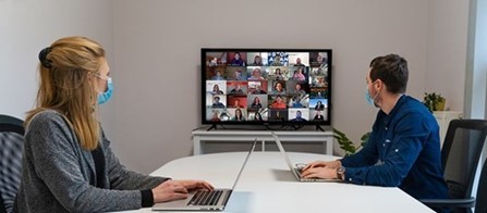 Photo of two people at a table participating in a Zoom meeting