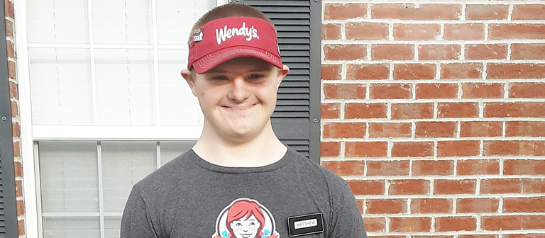   Photo of young man in Wendy's hat  and shirt in front of a window