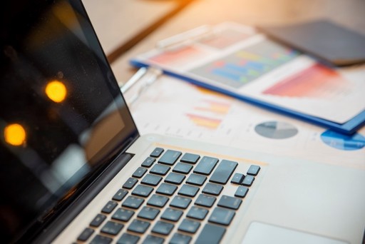 photo of a laptop and printed charts beside it