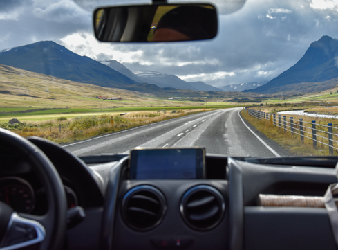  Photo taken from inside a car through the windshield of road ahead with mountains in the distance