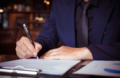photo of hand with pen signing a clipboard