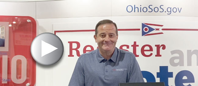 Photo cover of Director Miller at Secretary of State's booth at the Ohio State Fair and a play button