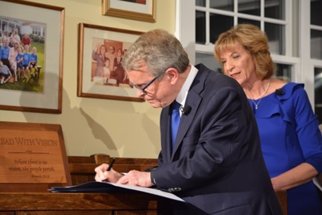 Governor DeWine signing Executive Orders standing next to his wife Fran