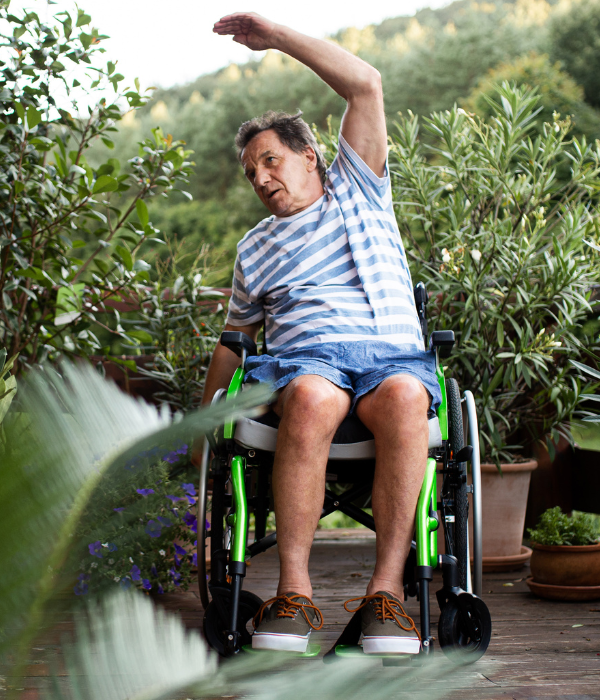 Man in wheelchair with arm above his head.