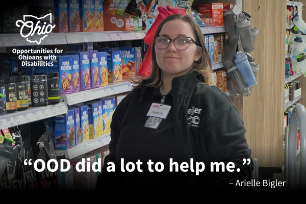 Girl smiling at the camera standing in front of grocery store shelves stocked with boxed goods.