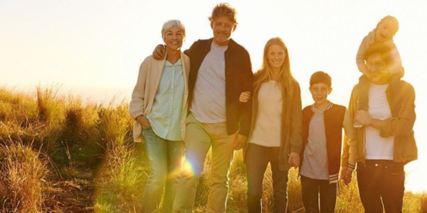 Family of six with multiple generations stands together in a group in a field.