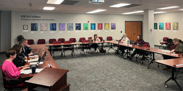 Seven individuals seated in a conference room during a meeting.