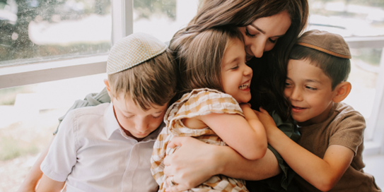 Woman, two boys, and one girl hugging and embracing each other.