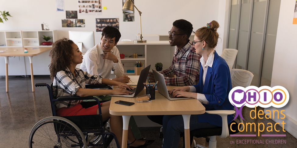 Four people collaborating around a desk workspace.