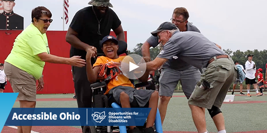 Participant in a wheelchair is cheered on by a team of supporters at an event.