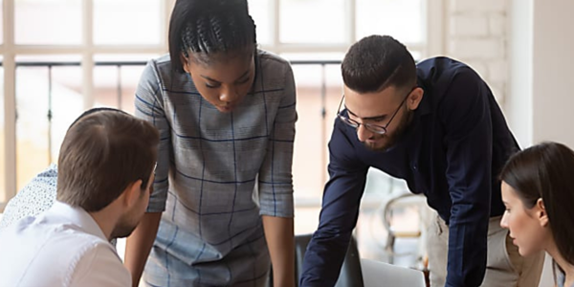 Four people looking at something on a desk together.