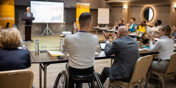 A group of individuals applauding a speaker during an accessible meeting.