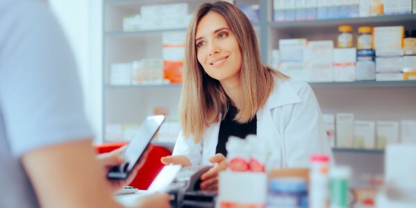 A pharmacist assisting a customer, who is holding a mobile device.