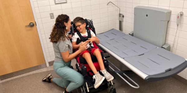 Kim Kirkwood and Aiden Boulter beside a universal changing table in an accessible restroom.