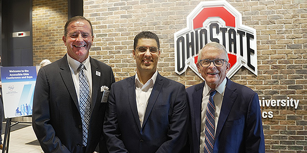 Director Miller, Governor DeWine, and Sam Sepah in front of a brick wall with "OSU" on it.