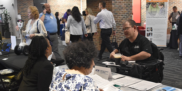 Josiah Lanning in a motorized wheelchair at a vendor's table at the conference