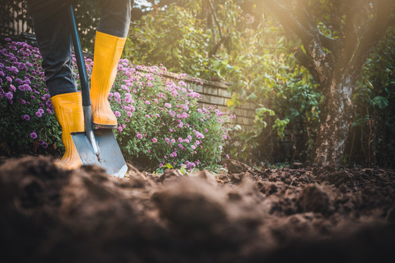 Person wearing yellow boots using a shovel to dig
