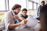 Male teacher showing a paper to a male student