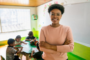 Female teacher standing in classroom with students sitting behind her