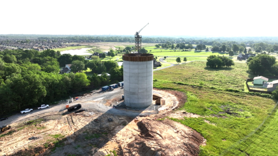 This picture has the new elevated water storage tank at 80 feet tall. There are houses and trees in the background .