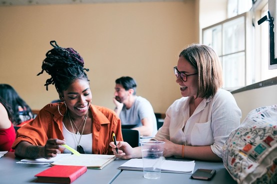 student at a table talking to a teacher