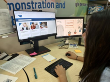 Side profile view of a woman with olive skin and very dark hair. She is viewing the Accessibility Course Catalog on her left desktop monitor