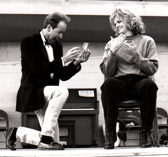Man kneeling in front of woman who is communicating American Sign Language.