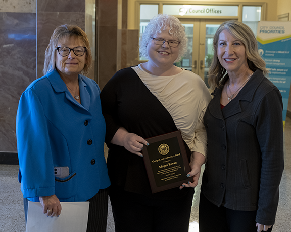 Three woman with one holding award.