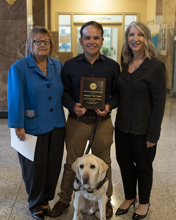 Man holding an award with a woman pon both sides.