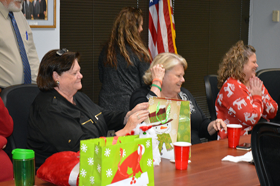 Three women at table with Christmas presents on table.